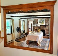 Full view of the large square wall mirror with natural wood frame reflecting a room interior.