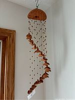 Full view of the hanging clay windchime with sombrero-shaped pieces and beads suspended from a rounded top.