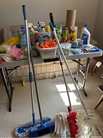 Wide view of cleaning supplies on fold-up table with two mops in front
