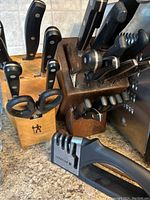 Two wooden knife blocks filled with knives and kitchen shears, and a Sabatier knife sharpener in front.