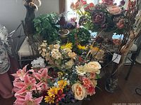 Wide view of assorted faux flowers and containers, including pink lilies, cream roses, and greenery