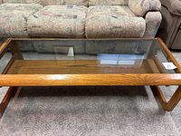 Top angled view of the oak coffee table showing clear glass insert and wood grain surface.
