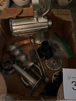 Photo shows Porkert metal meat grinder components in a box including auger, plates, handle, and body parts.