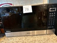 Front view of a black Panasonic microwave oven with stainless steel bottom trim and digital control panel on right side.