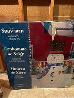 Box showing image and description of large outdoor snowman with 300 LED lights, labeled in English, French, and Spanish.