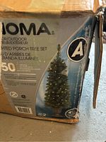 Box showing brand JOMA and features of the lighted porch tree set, 4 ft height, 50 multicolor minilights, suitable for indoor/outdoor use.