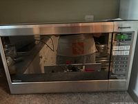 Front view of stainless steel Panasonic inverter microwave with reflective door.