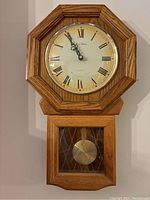 Full view of Daniel Dakota Westminster chime pendulum wall clock with visible clock face, pendulum, and wood frame.