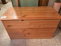 Side view of wooden trunk showing natural wood grain and hinged lid.