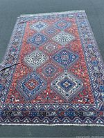 Full view of rectangular area rug laid flat on pavement showing overall geometric pattern and colors.