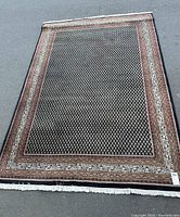 Full view of rug laid flat on pavement, showing overall geometric pattern and border