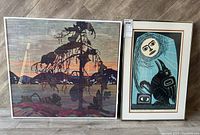 Photo showing both framed art prints side by side on floor: Tom Thomson reproduction and Aboriginal art print