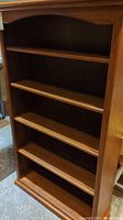 Front view of the wooden bookcase showing all five shelves and overall condition.