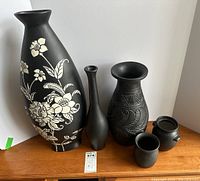 Full set of five decorative ceramic vases and jars with varying shapes and designs, black matte finish with white floral and engraved details.