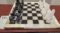 Full view of chess set on the board showing all pieces arranged for play, black and white stone pieces on black and white checkered stone board with stone border.