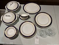 Overview of partial dinner set including covered dishes, plates, gravy boat and glass bowls.