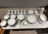 Full view of the dinnerware set arranged on a table showing various plates, cups, saucers, teapot, sugar bowl, creamer, salt and pepper shakers, and serving dishes.