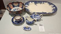 Overview of fine china lot showing Royal Crown Derby platter, Royal Crown Derby creamer and lidded sugar bowl, Royal Dalton bowl, and blue and white teacup with saucer.
