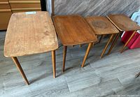 View of all four wooden Mid-Century Modern style nesting tables side by side showing size differences and general wear.