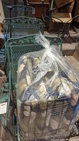 View of bundled cushions tied in plastic placed on top of stacked green metal mesh chairs with floral accents