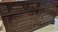 Front upper section showing three smaller drawers with brass ring pull handles and carved wooden detailing.