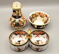 Porcelain shaker and two condiment bowls showing Imari pattern with floral and gold detailing.