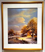 Framed oil painting showing winter landscape with snow-covered house and trees, people on frozen river, cloud sky in warm tones. Framed in vintage wood frame with white painted panels.