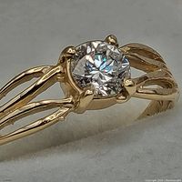 Close-up of ring on white pad showing split shank and round diamond