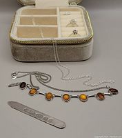 Jewellery box open with two sterling silver necklaces (one with amber stones), vintage sterling silver letter opener stamped CG&SCo '925' with Birmingham anchor, and cuff earrings and rings inside box compartments.