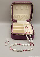 Photo showing set with zippered purple velvet storage box, necklace and earrings placed inside and outside box for display