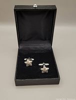 Pair of starfish-shaped sterling silver cufflinks displayed in a black velvet-lined presentation box, black exterior box visible.