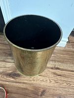 Full view of cylindrical brass garbage can with black interior