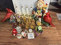 Lot of Christmas-themed decorative items including cardinal bird figurines, snowman, nativity figures, Santa Claus figures, clear owl figurine, snow globe and LED candle lights