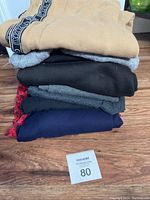 Stack of folded assorted ladies clothing displayed on wooden surface with Masold lot number tag visible.
