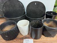 Front view of six assorted planters on wooden surface showing variety of styles and signs of use.