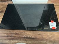 Rectangular black marble cutting board with polished surface and natural marble pattern, showing minor wear.