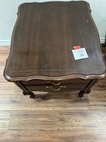 Top view of dark wooden night table showing scalloped edge and wear marks.