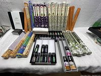 Overview showing multiple packages of HEM incense sticks, bottles of scented oils, and wooden incense holders arranged on a surface.