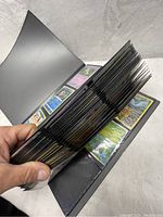 Open binder with pages of foil Pokémon cards visible, showing several rows of cards in plastic sleeves.