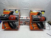 Two Black & Decker rechargeable spotlights in boxes, one opened, one unopened, and a separate box for an additional rechargeable spotlight.