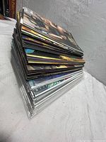 Stack of 60 comic books showing various covers and spines packed together in a pile with some in plastic sleeves.