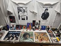 Full lot showing Michael Jackson T-shirts, vinyl albums, CDs, and memorabilia spread out on a surface.