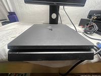 Front face view of black Sony PS4 Slim gaming console on table.