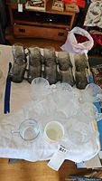 Overview photo showing multiple glass mugs on a table, including dark tinted glasses and clear/milk glass mugs.