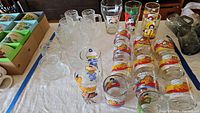 Overview of 18 glasses including McDonald's character glasses and Garfield mugs arranged on a table.