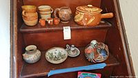 Full collection of pottery items including duck figurine, small cups, bowls, lidded crock, and candle holder arranged on steps
