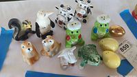 A group photo showing thirteen ceramic salt and pepper shakers shaped like various animals and eggs including skunk, eagle, dogs, cow, owls, frog, and bird.