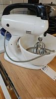 Side view of Sears 12-speed stand mixer in white with black handle and attached mixing bowl on wooden surface.