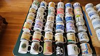 Overview of 35 Starbucks city mugs arranged in rows on a table