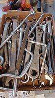 Photo showing assorted rusty Craftsman wrenches and crowfoot wrenches piled in a box.